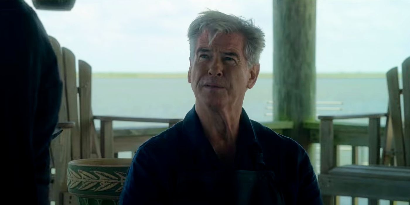 Pierce Brosnan sitting on a dock by a lake in Fast Charlie.