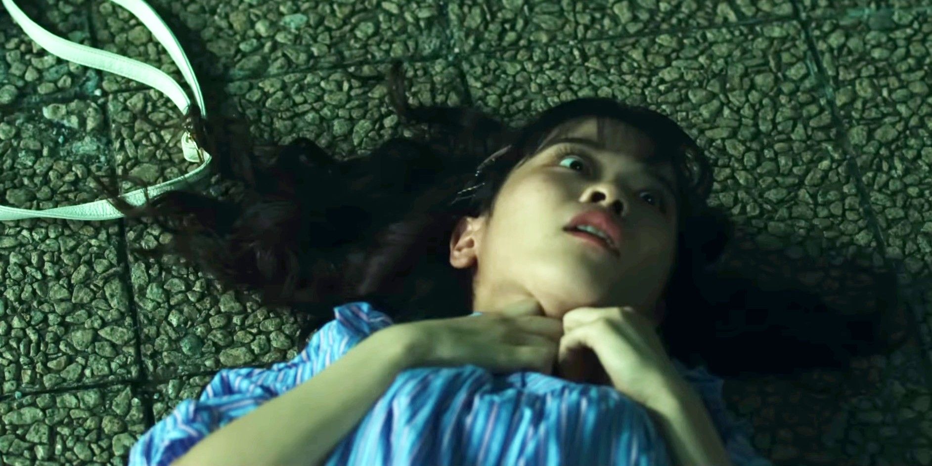 Character on the ground with wide eyes holding their neck in Sadako DX
