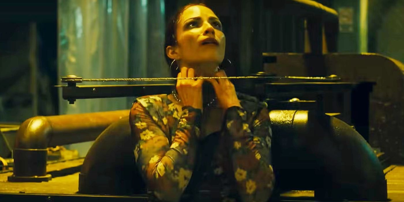 A woman looking terrified and clawing at a metal collar around her neck in Saw X.