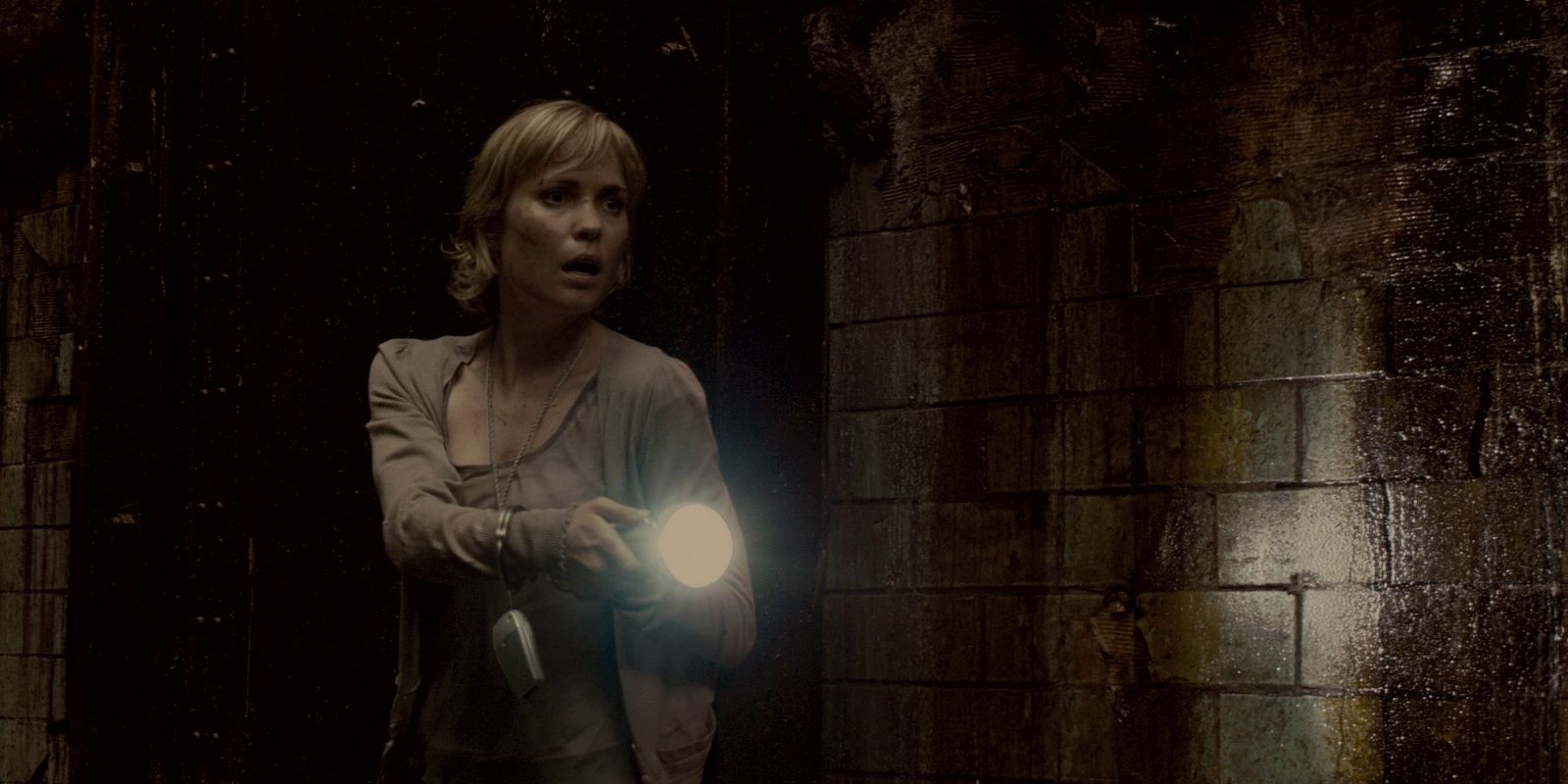 The heroine looks down a dark hall with a flashlight in Silent Hill 2006