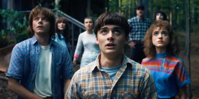 Jonathan, Will, Nancy, Eleven, Joyce, Hopper, and Mike looking up at the sky in the final scene of Stranger Things season 4.
