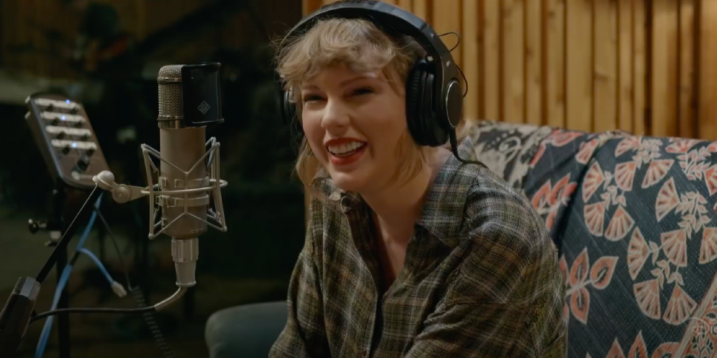 Taylor Swift recording in a studio and smiling in Folklore