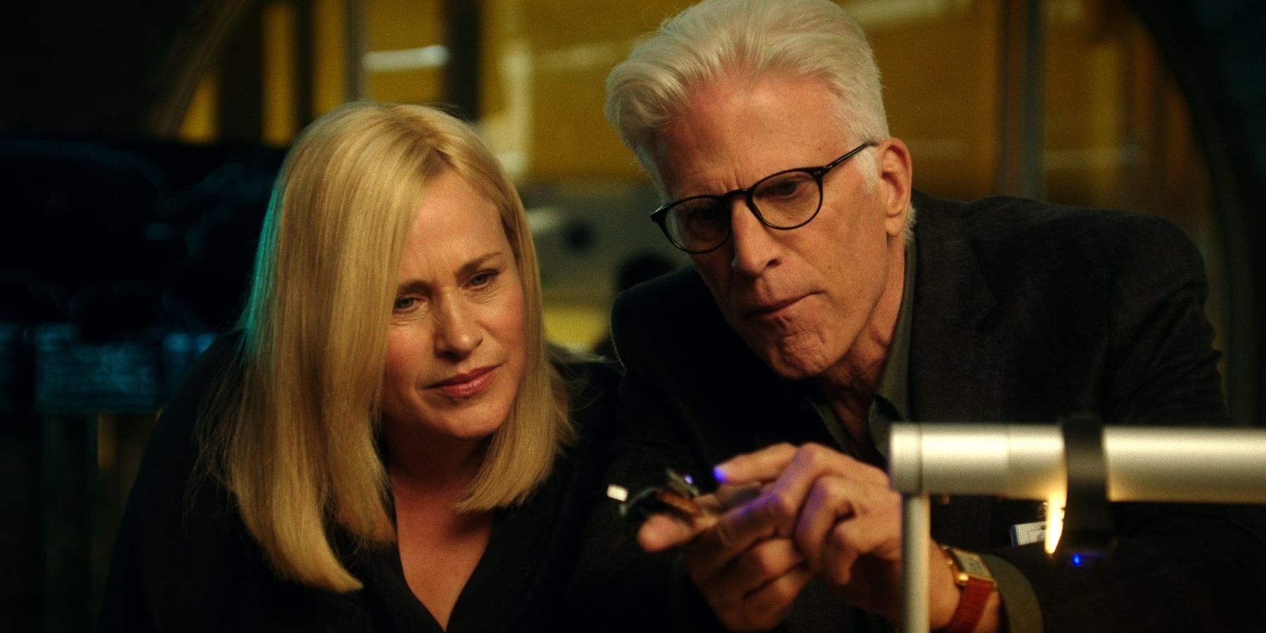 Ted Danson and Patricia Arquette looking at a piece of technology together in CSI: Cyber