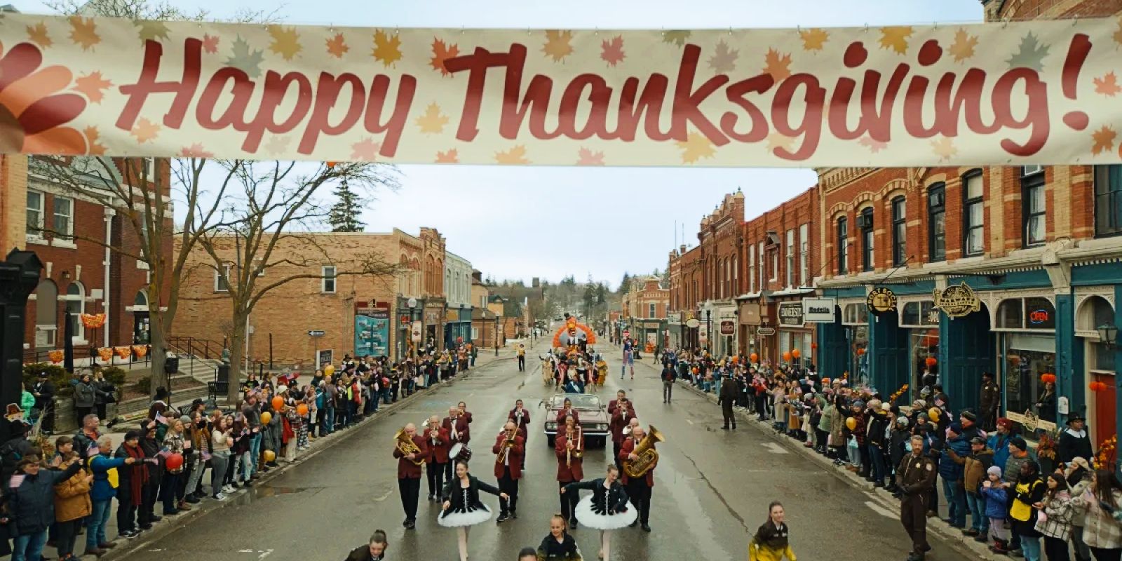 This image shows a Thanksgiving parade with people watching from the sidewalks.