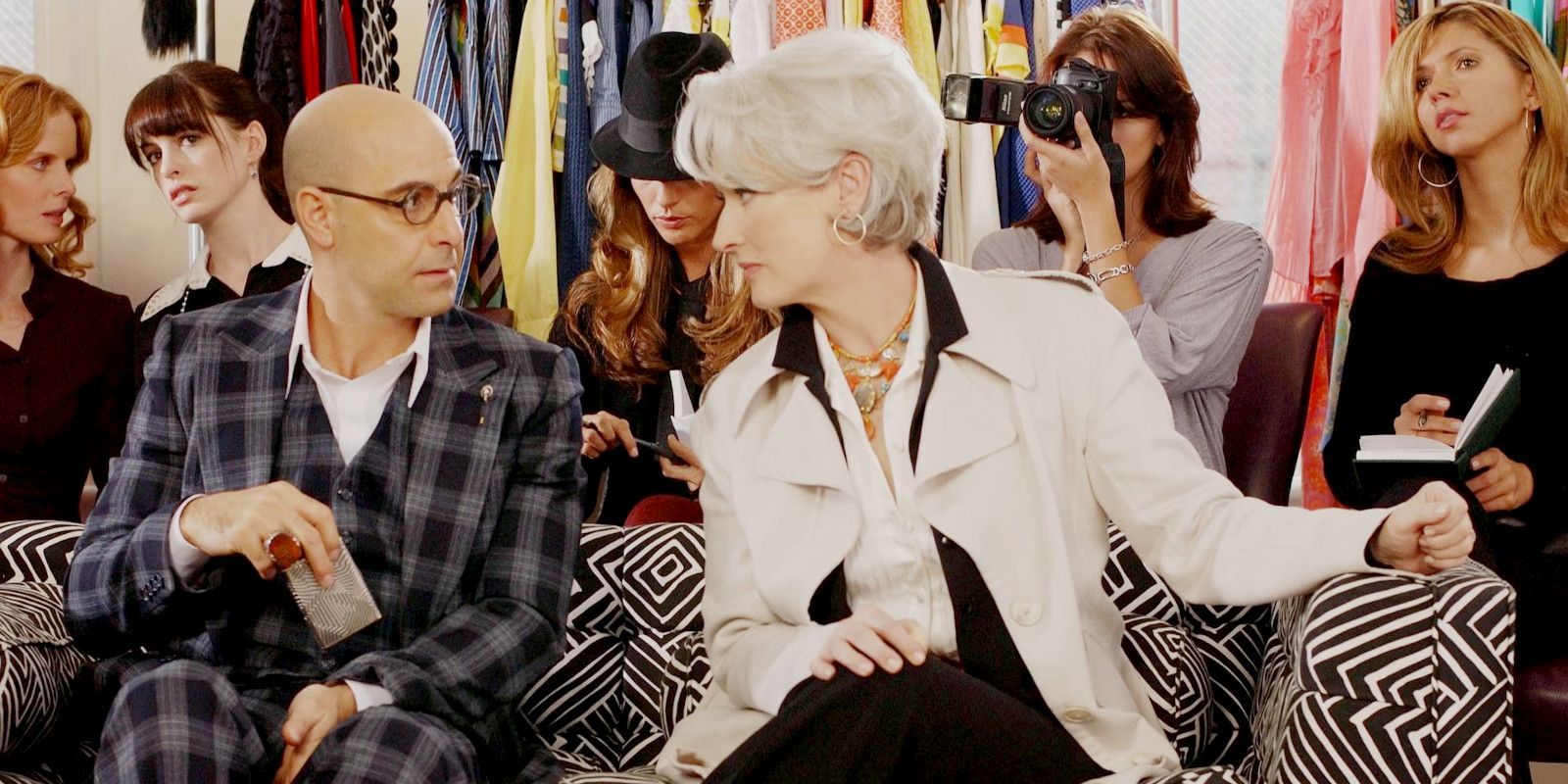 Nigel (Stanley Tucci) and Miranda (Meryl Streep) sitting next to each other on a couch during a fashion show in The Devil Wears Prada.