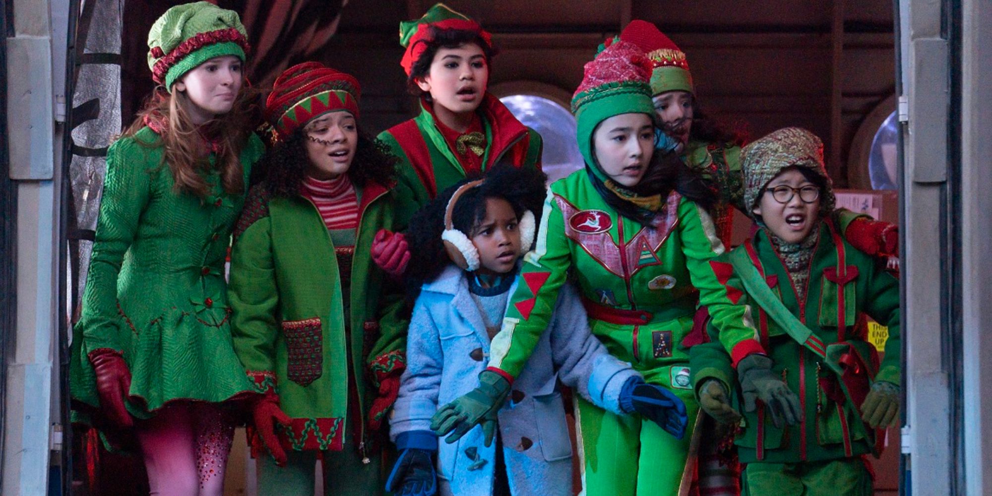 The kids dressed in red and green elf outfits at the door of a plane in The Naughty Nine