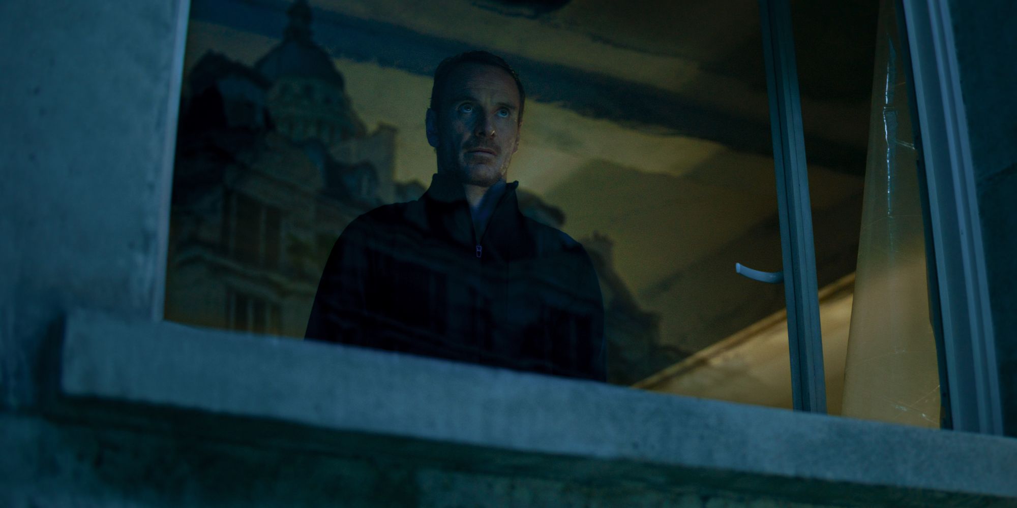 Michael Fassbender como el asesino titular mirando por una ventana en The Killer