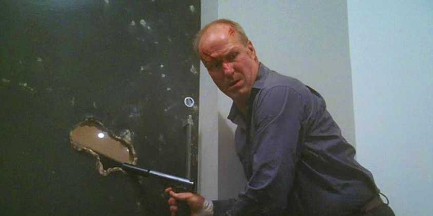 William Hurt holding a pistol and looking over his shoulder in Nightmares and Dreamscapes.