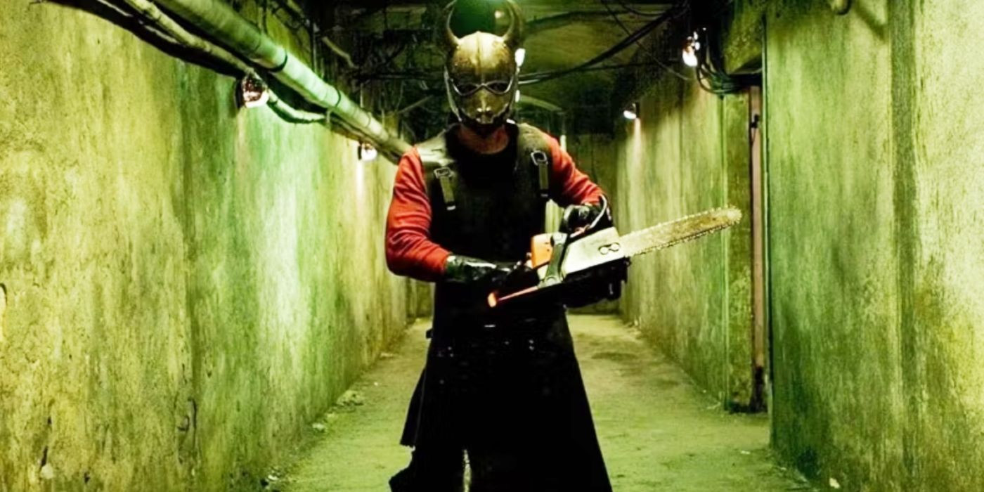 A man wearing a horned mask and apron wield a chainsaw in a hallway in Hostel.
