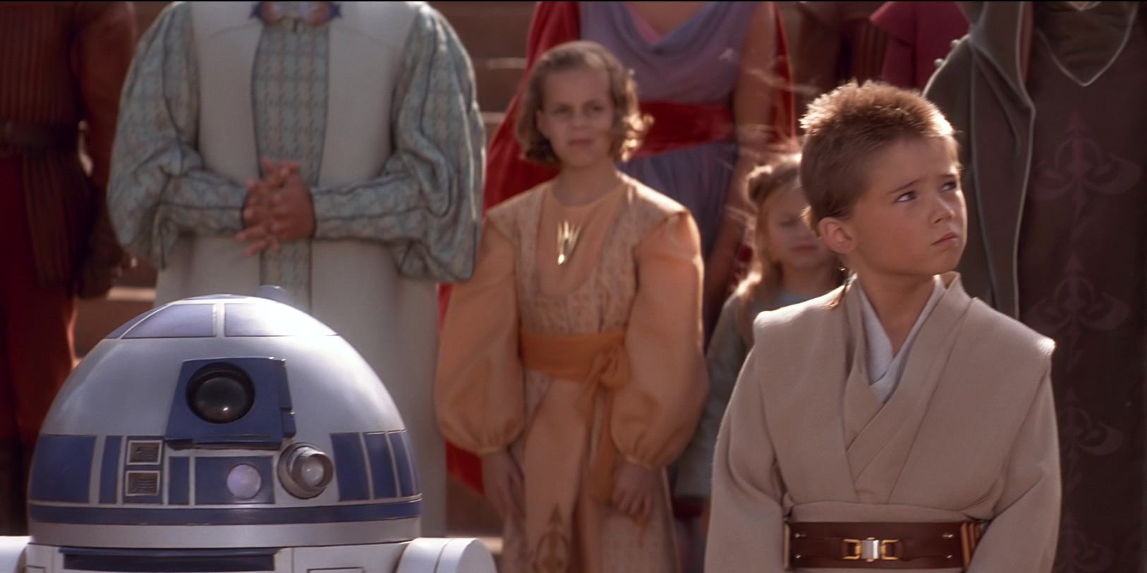 Anakin muda mendongak dan R2-D2 berdiri di sampingnya di The Phantom Menace