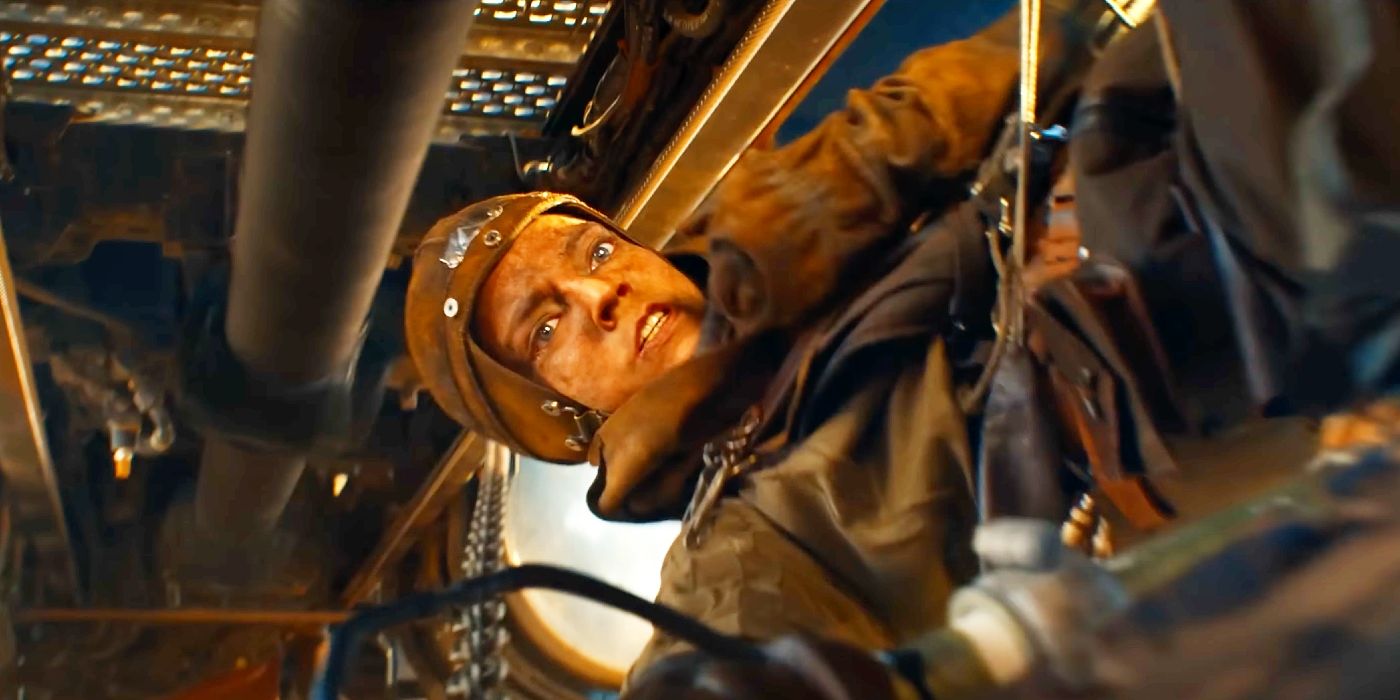 Anya Taylor-Joy as Furiosa hanging onto the bottom of a big rig truck.