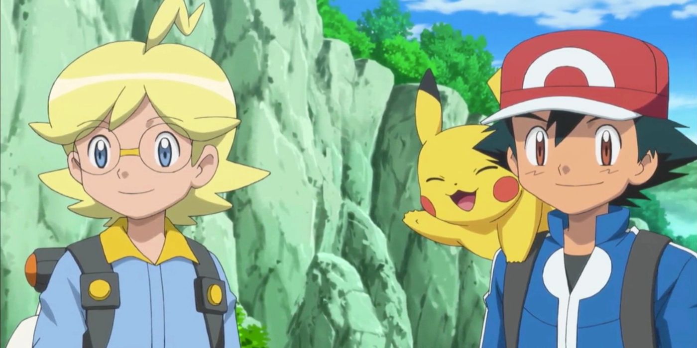 A boy with yellow hair and glasses stands next to a boy with a red hat and a yellow mouse-like creature on his shoulder.