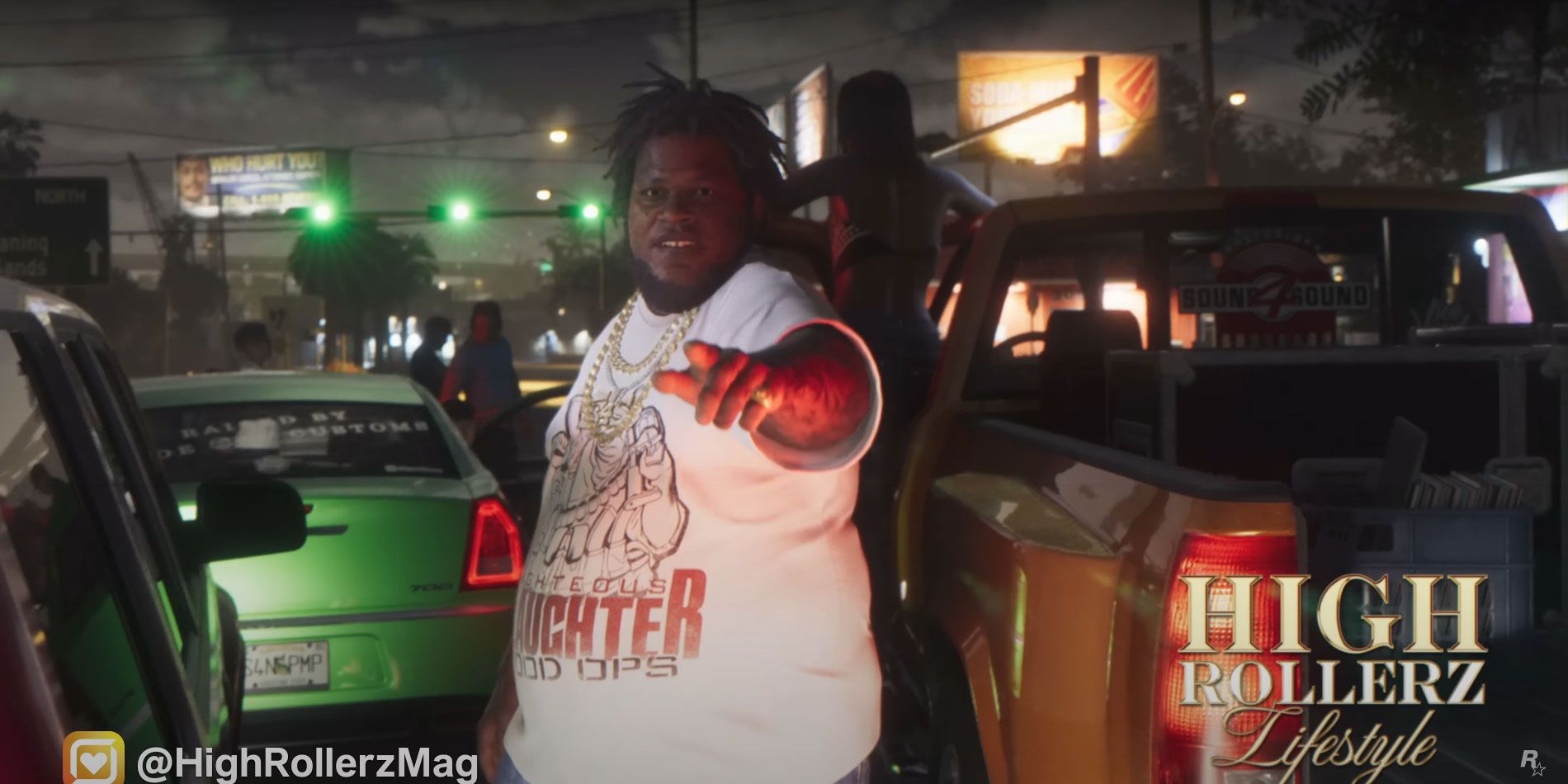 A man pointing toward the camera with impressive cars around it.