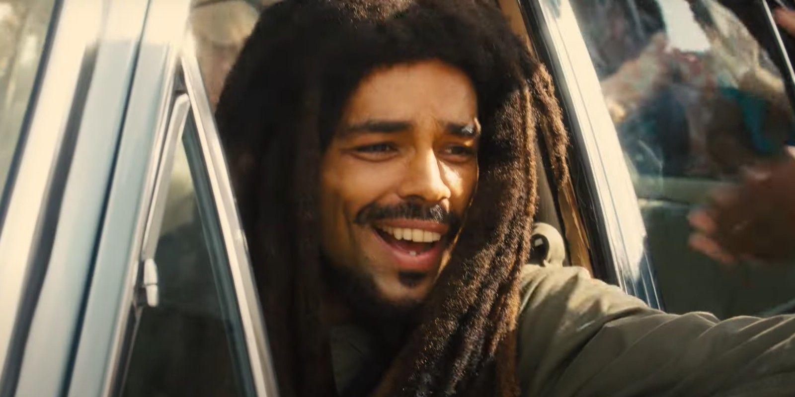 Bob Marley (Kingsley Ben-Adir) estendendo o braço para fora da janela do carro em Bob Marley: One Love