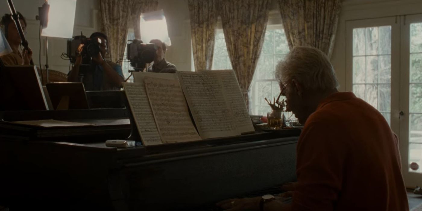 Bradley Cooper as old Leonard Bernstein at the piano in front of cameras in Maestro