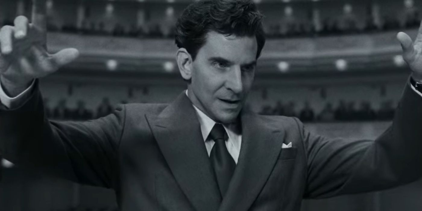 Bradley Cooper as Leonard Bernstein in black and white conducting his first show in Maestro