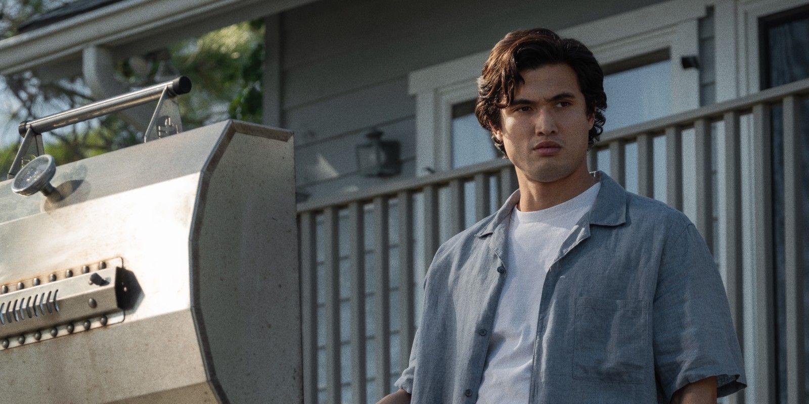 Charles Melton as Joe standing in front of a grill in May December