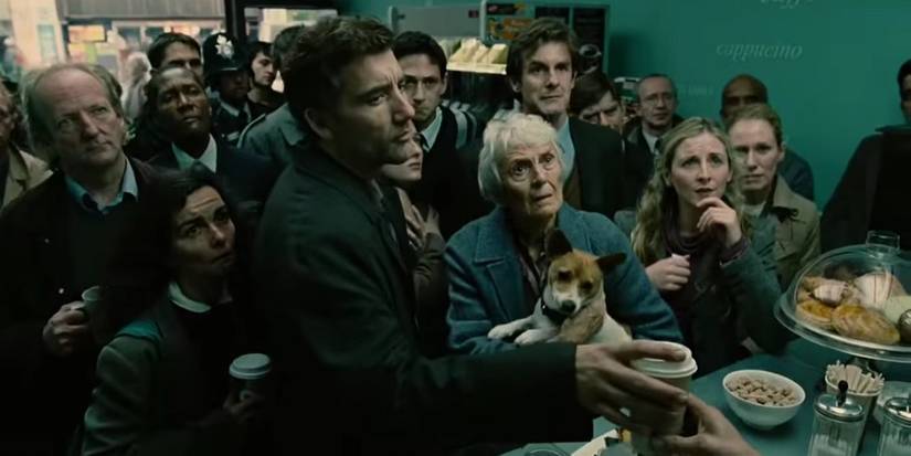 Theo (Clive Owen) and a crowd of people standing in a store looking at a tv in Children of Men opening scene
