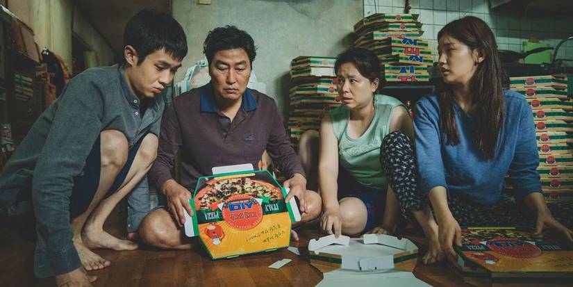 Choi Woo-shik, Song Kang-ho, Jang Hye-jin, and Park So-dam as the Kim family fold pizza boxes on the floor in Parasite