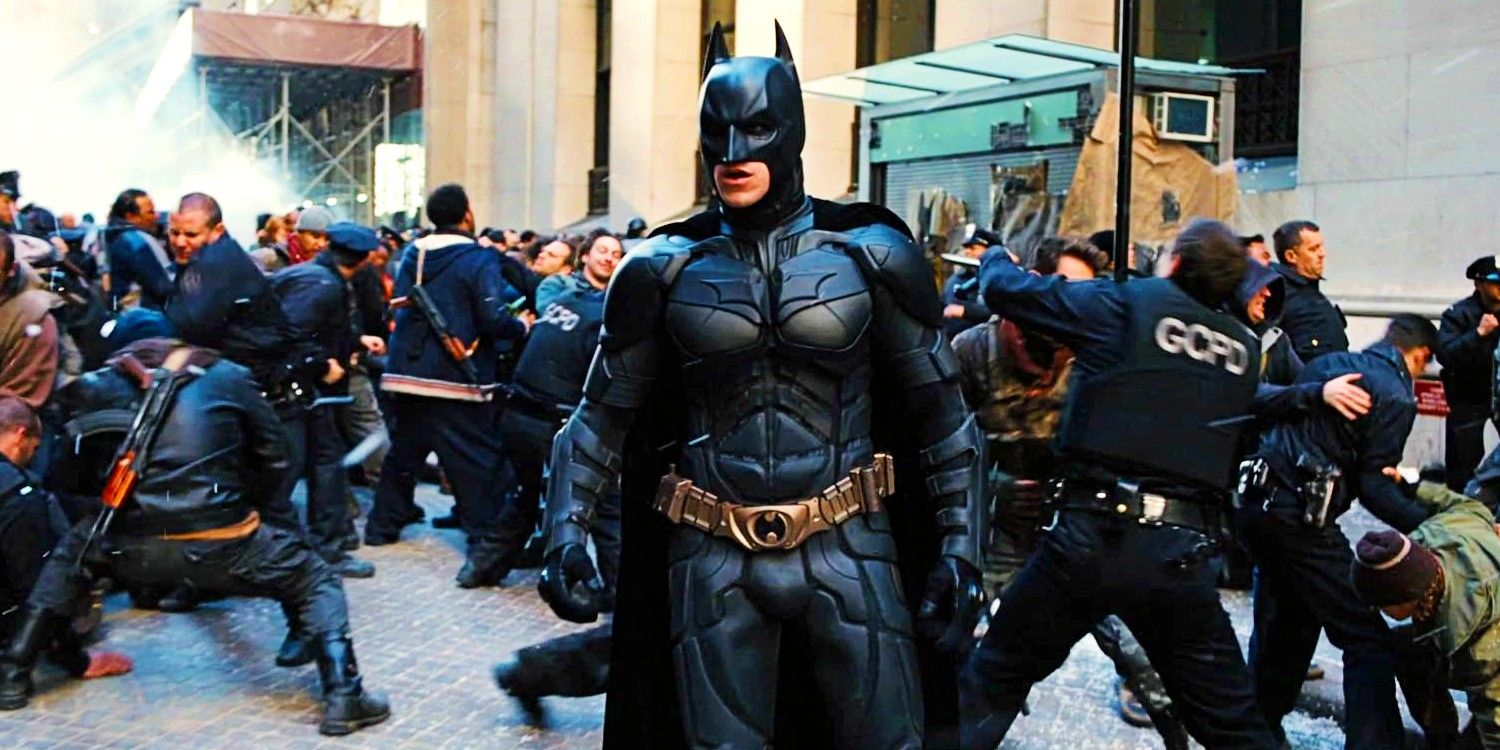 Christian Bale As Bruce Wayne In Full Batman Suit Standing Amid A Riot In The Dark Knight Rises