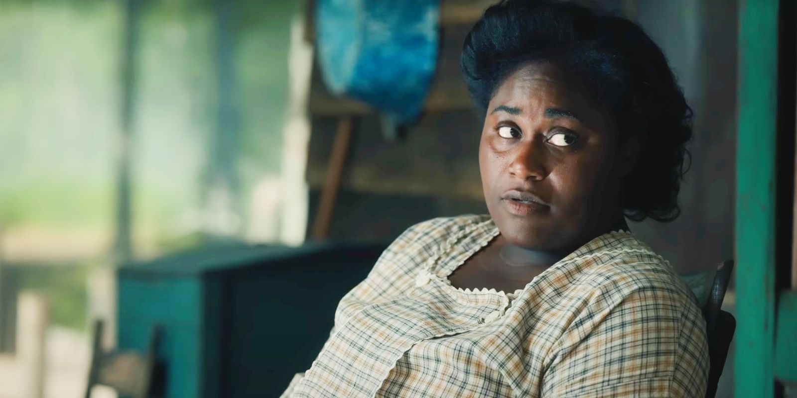 Danielle Brooks as Sofia sitting on a porch chair in The Color Purple