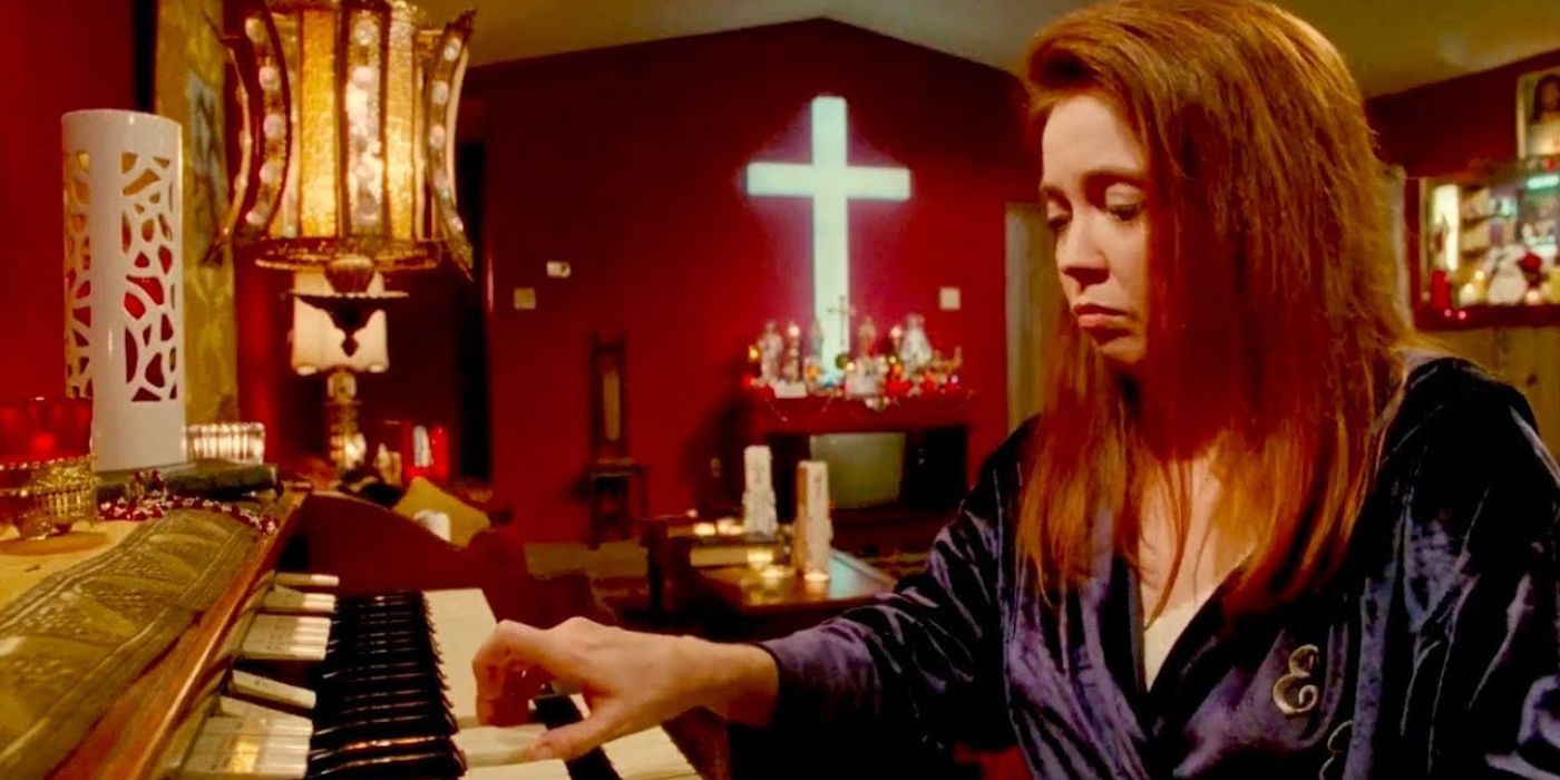 Esmeralda solemnly plays her organ inside her Christian memorabilia-occupied room in a scene from Edward Scissorhands
