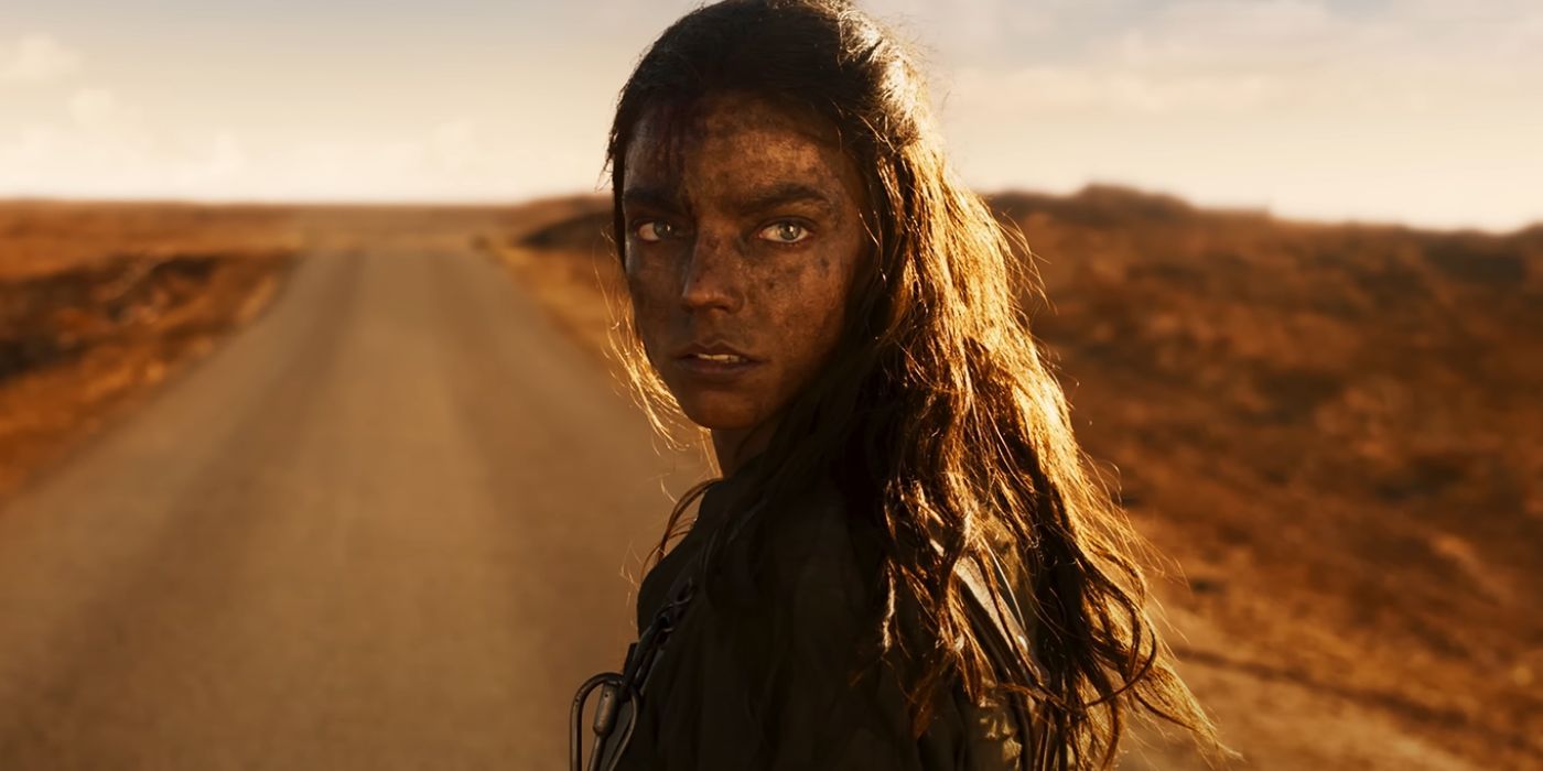 Furiosa (Anya Taylor-Joy) olha por cima do ombro esquerdo para uma pessoa desconhecida enquanto está parada no meio da estrada em Furiosa