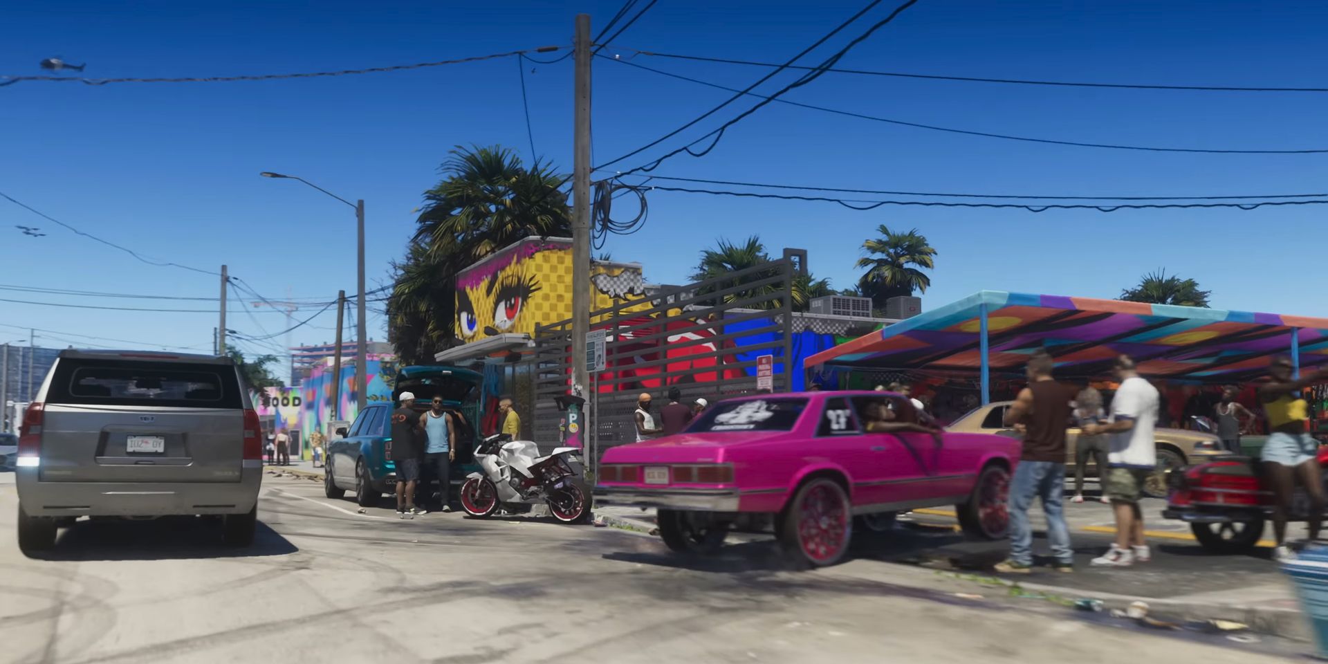 A Wynwood-inspired street in the first trailer for GTA 6. A magenta car drives into a parking lot of a building covered with colorful murals, including a giant pair of eyes looking down on the adjacent road.