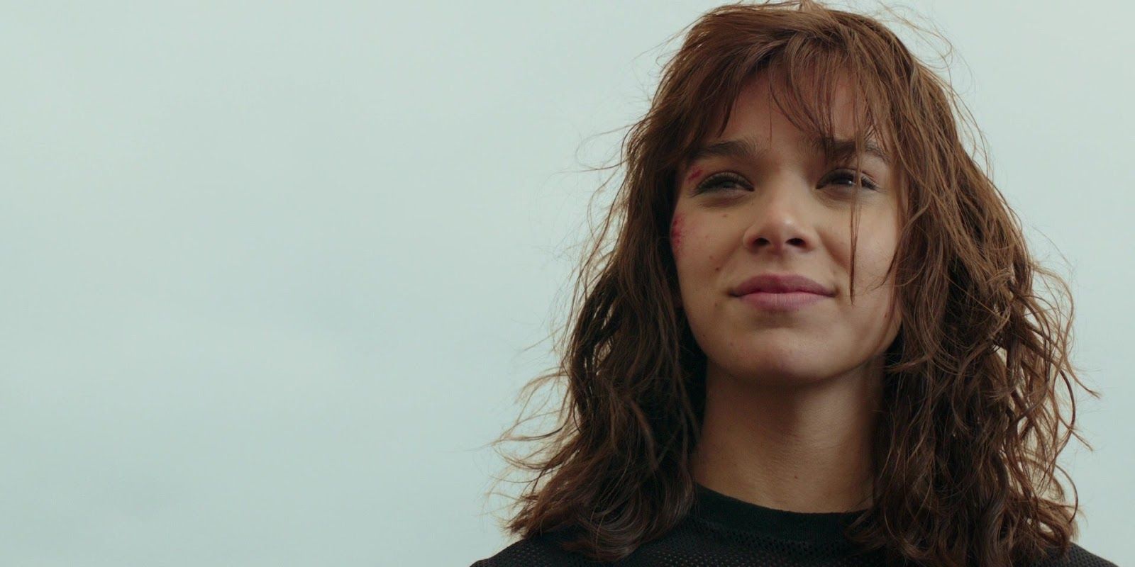 Charlie (Hailee Steinfeld) with cuts on her face, smiling in Bumblebee