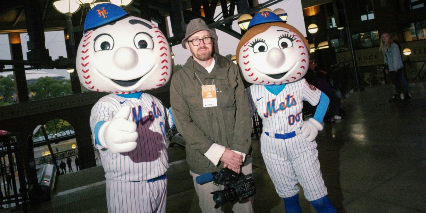 John Wilson standing with the mascots for The Mets in How To With John Wilson