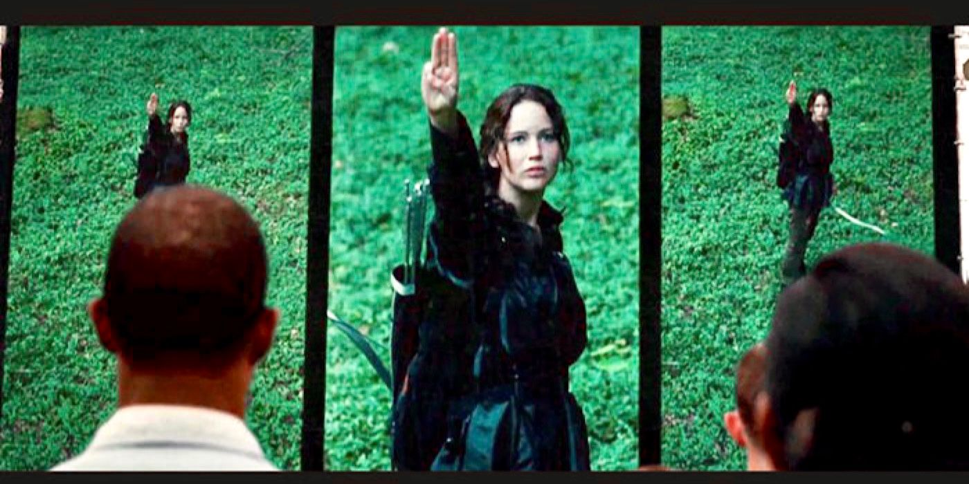 Katniss holds three fingers up to the cameras in The Hunger Games.