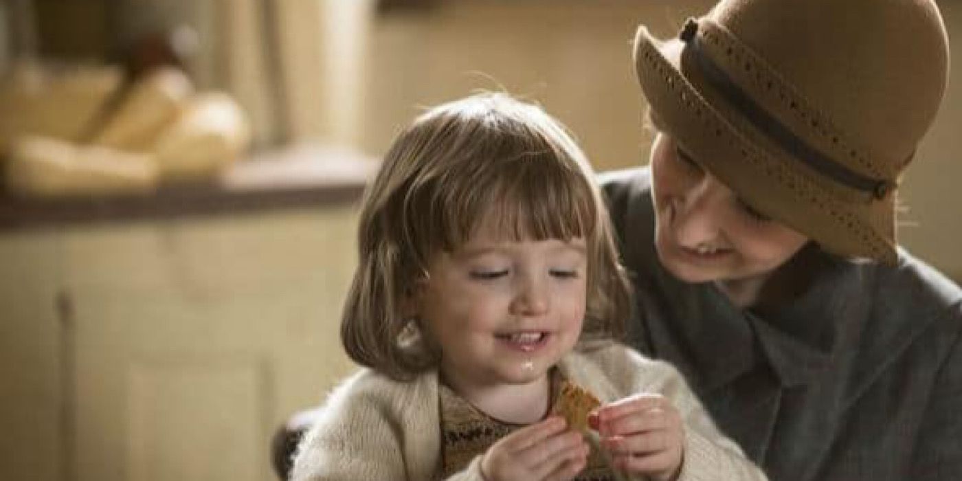 Marigold Gregson smiling while eating and sitting on her mother, Edith's, lap on Downton Abbey.