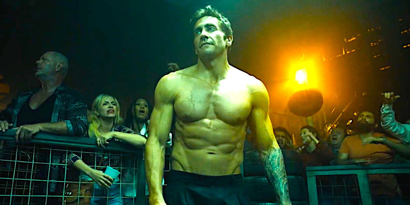 Jake Gyllenhaal shirtless and ripped, posing in a martial arts fighting ring surrounded by rabid fans, in a dramatic scene from Road House