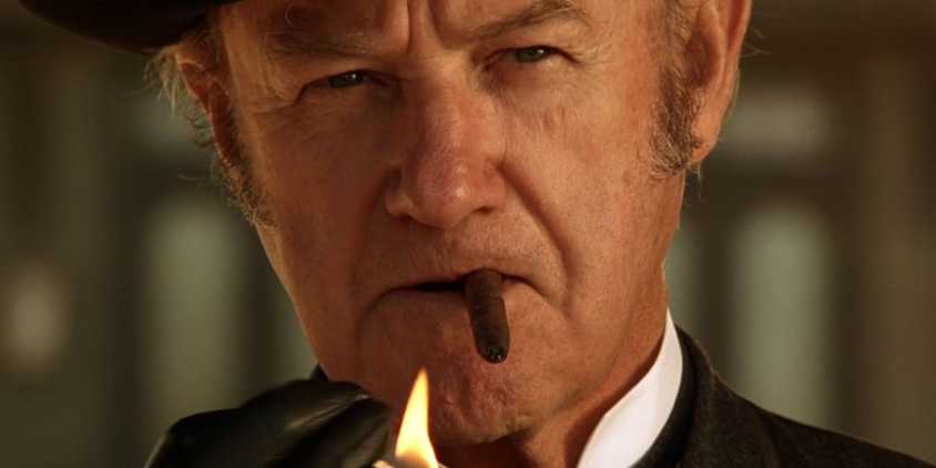 Gene Hackman as John Herod holds a light up to his cigar while squinting at an off screen foe in The Quick and the Dead