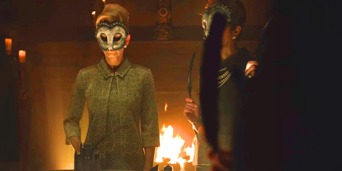 Gotham’s Kathryn Monroe wearing a Court of Owls mask next to another member in front of a fireplace