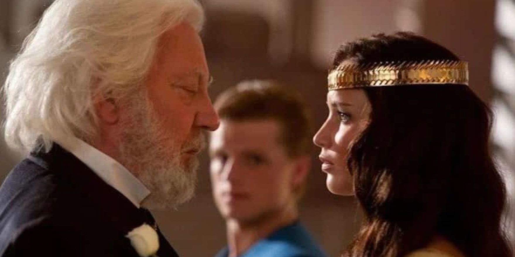 Katniss and Snow talking after her crowning while Peeta watches in Hunger Games