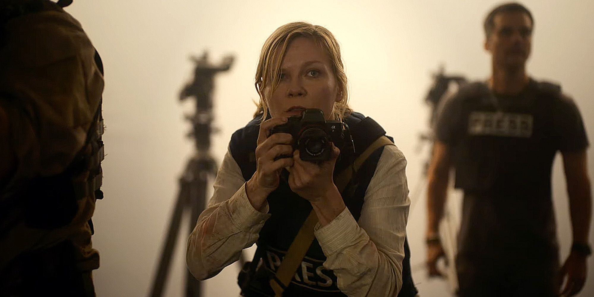 Kirsten Dunst as Lee with a camera while wearing a press vest in Civil War