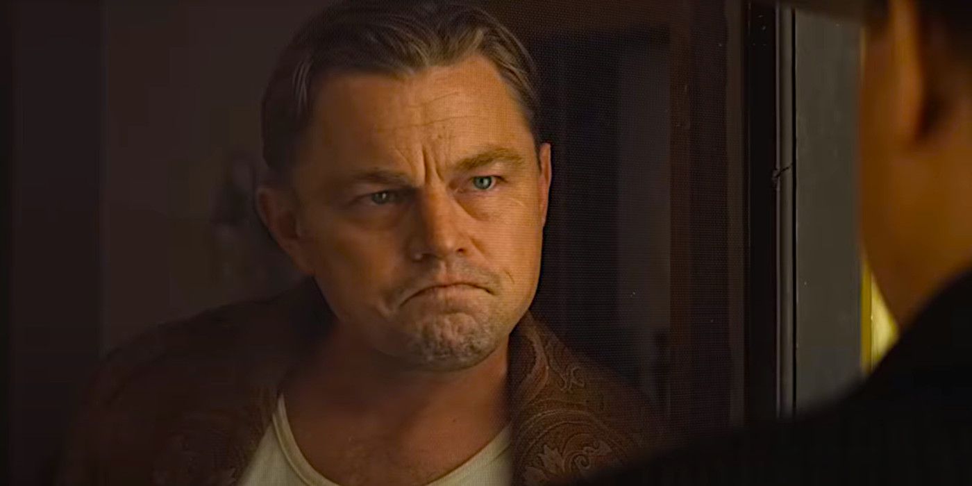 Leonardo DiCaprio frowning while speaking to someone through a door in Killers of the Flower Moon