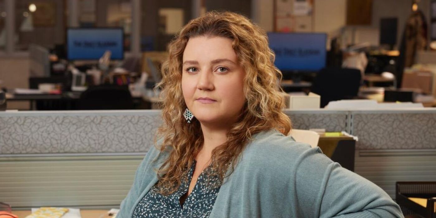 Meredith Holzman as Claire Muncy leaning back in her chair at her desk in Alaska Daily
