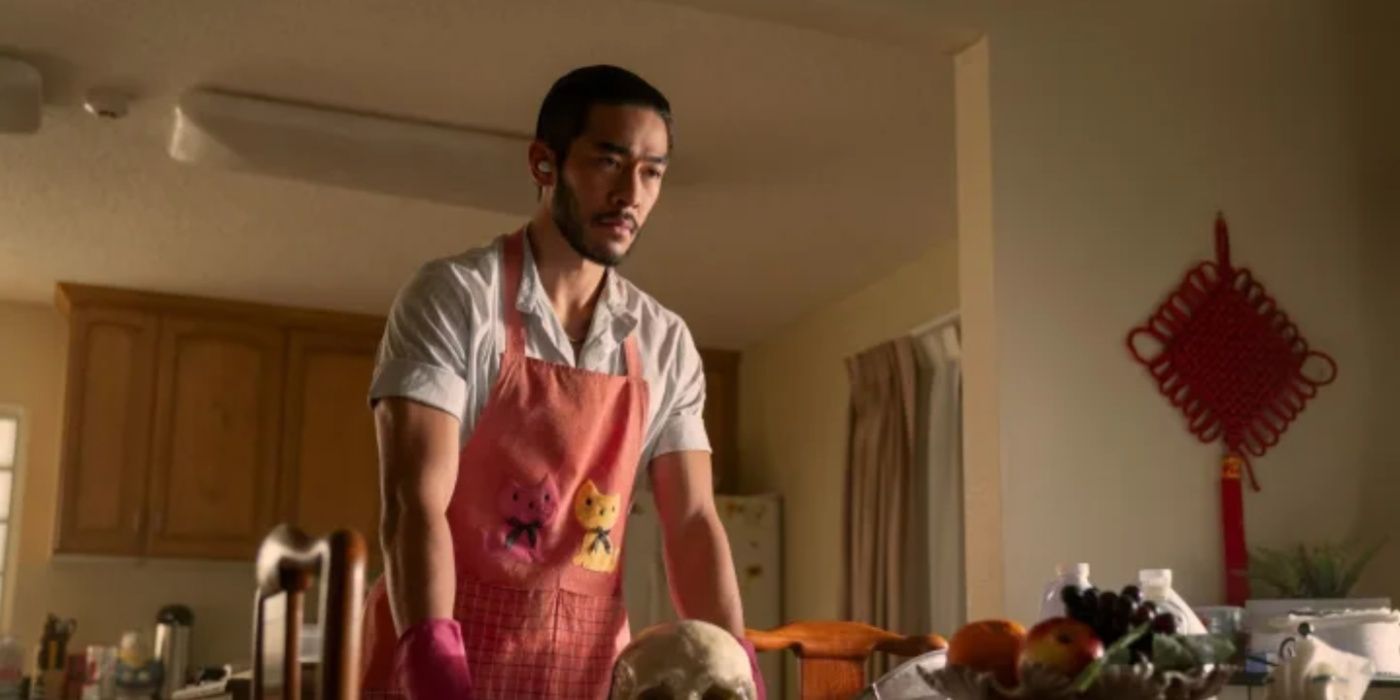 Charles (Justin Chen) wearing a pink apron in The Brothers Sun