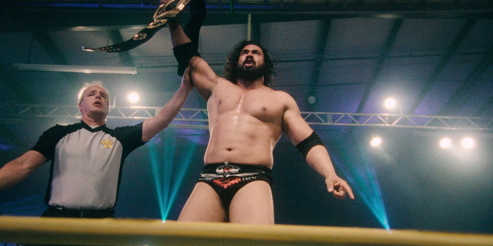 Mahabali Shera lifting his championship belt with a referee in the ring in the Netflix documentary series Wrestlers