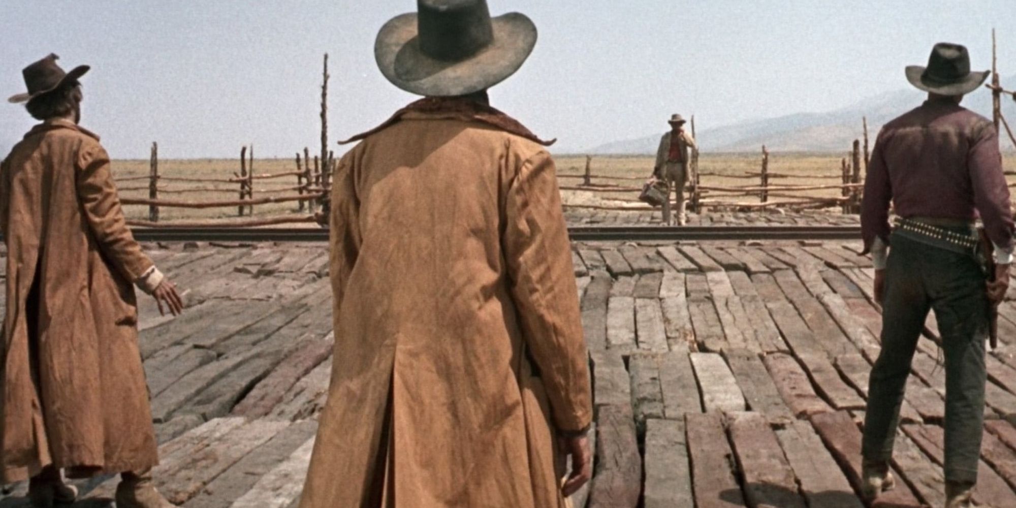 Charles Bronson como Harmonica se prepara para batirse en duelo con tres hombres armados a través de las vías del tren al mismo tiempo en el Oeste.