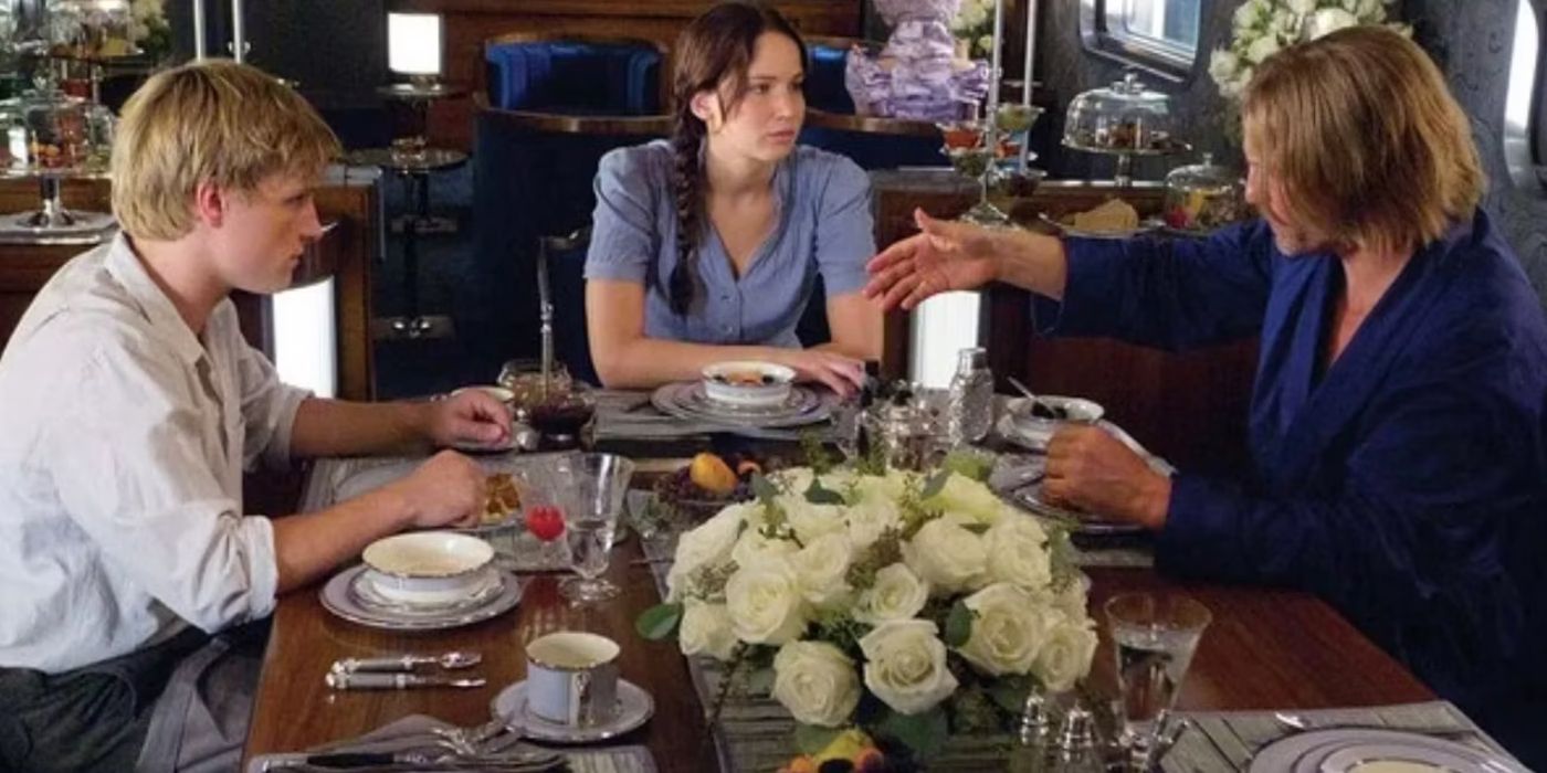 Peeta, Katniss, and Haymitch talk at the table on the train in The Hunger Games