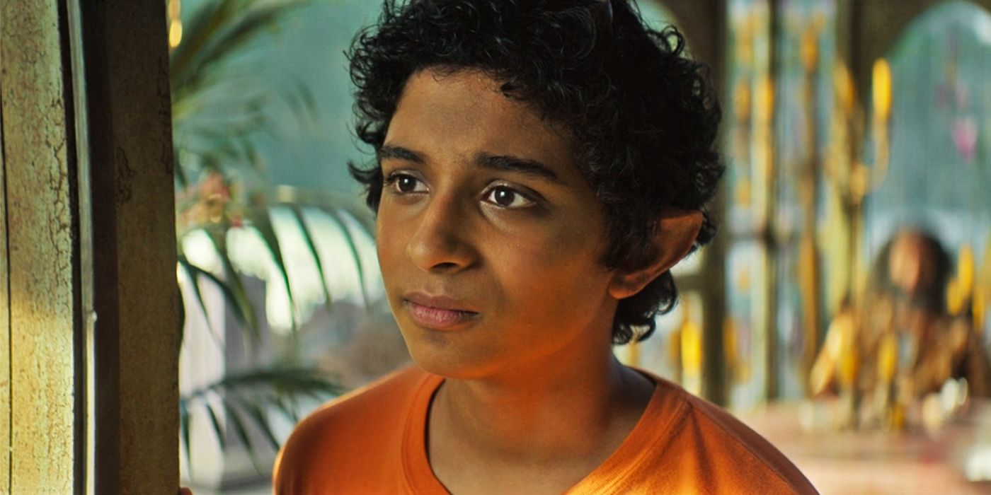 Close up shot of Aryan Simhadri as Grover wearing an orange Camp Half-Blood shirt in Percy Jackson and the Olympians looking somber