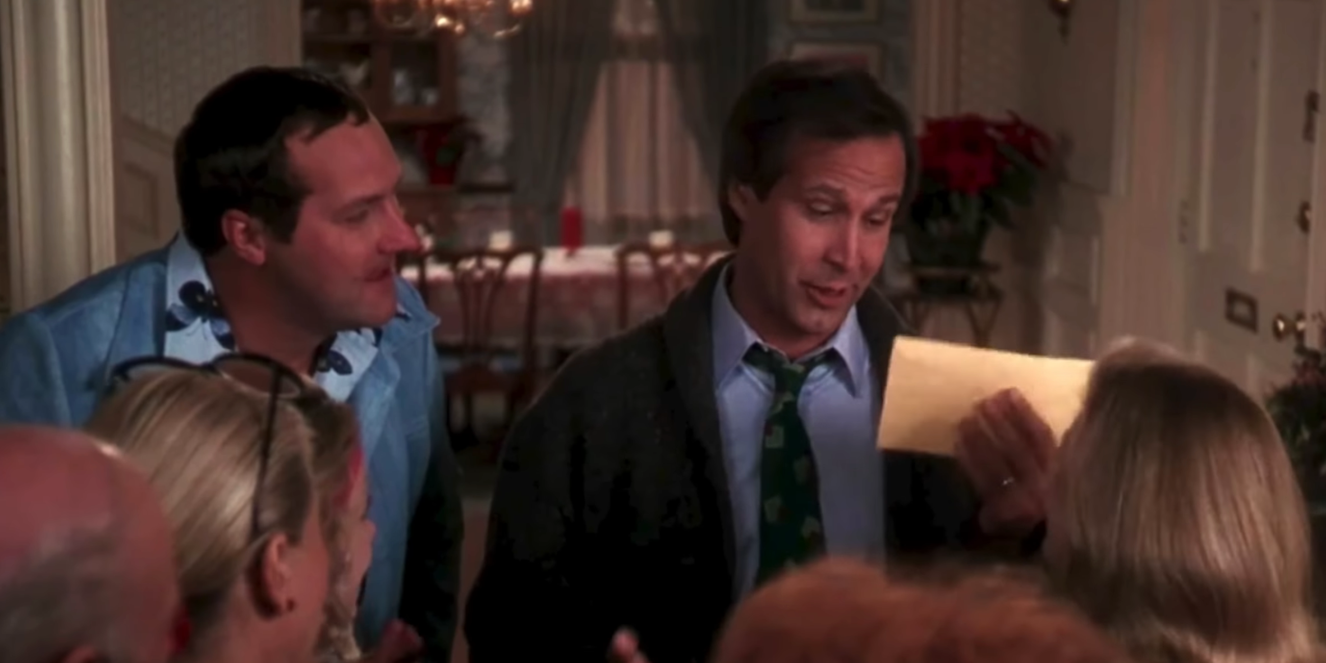 Randy Quaid as Cousin Eddie watching Chevy Chase as Clark Griswold hold an envelope in Christmas Vacation
