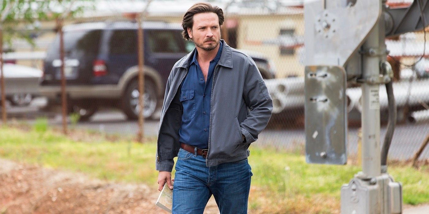 Daniel Holden (Aden Young) walking with a book in his hand