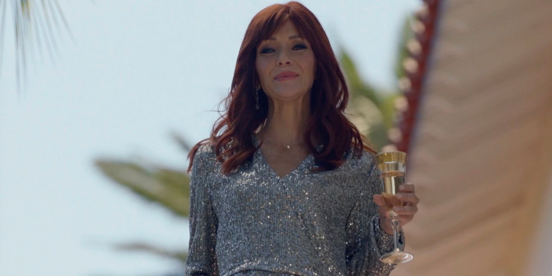 Rosalind (Annie Wersching) holding champagne and wearing a silver dress before she is killed in The Rookie