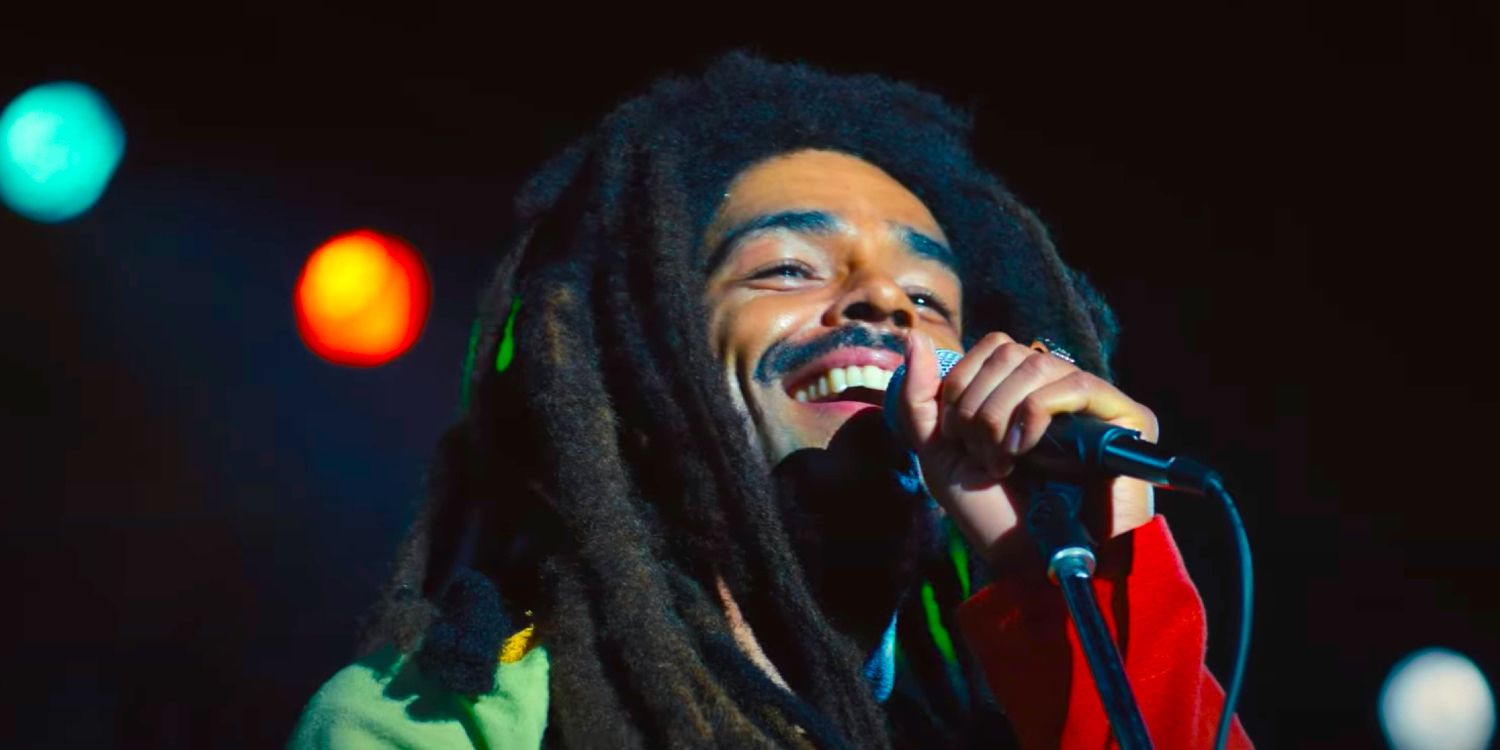 Kingsley Ben-Adir dans le rôle de Bob Marley souriant en chantant dans Bob Marley : One Love