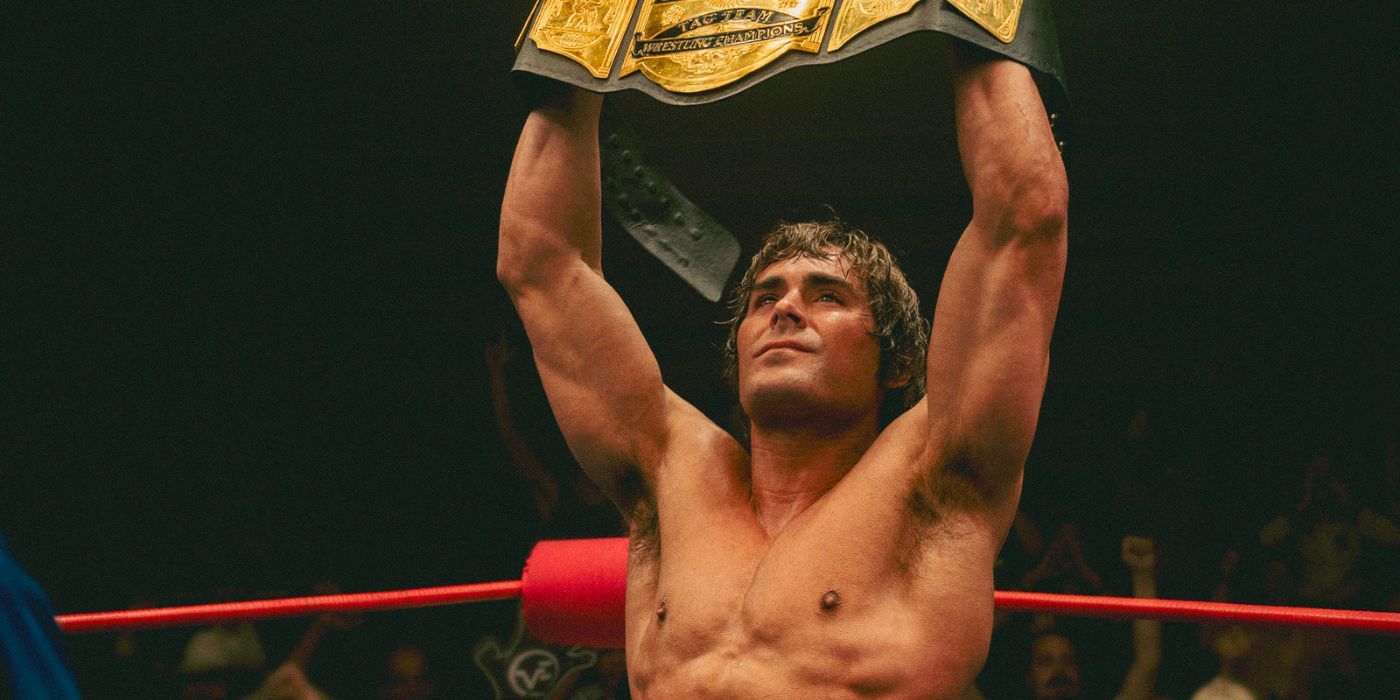 Zac Efron as Kevin Von Erich holding up a belt in the ring in The Iron Claw