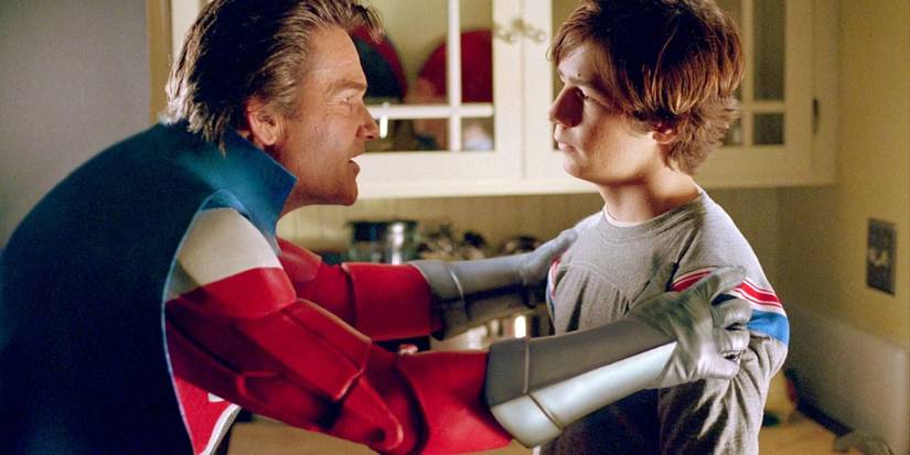 Kurt Russell in a superhero suit grabbing Michael Angarano by the shoulders in Sky High